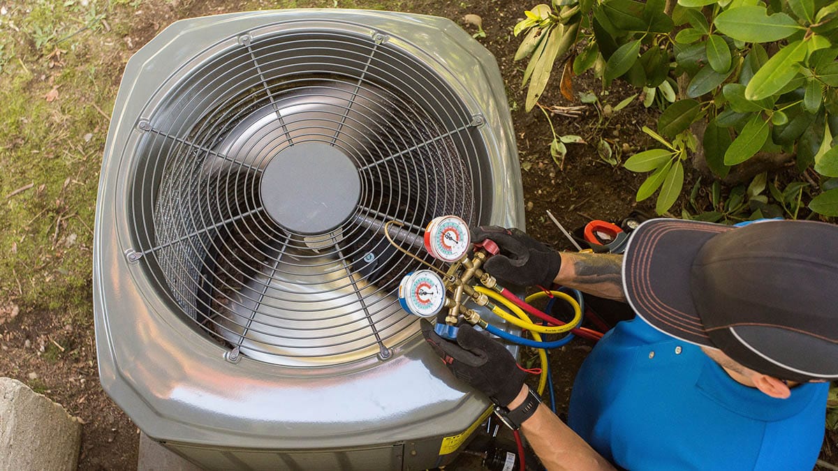 Photo from above of technician performing a maintenance test on an air conditioning unit