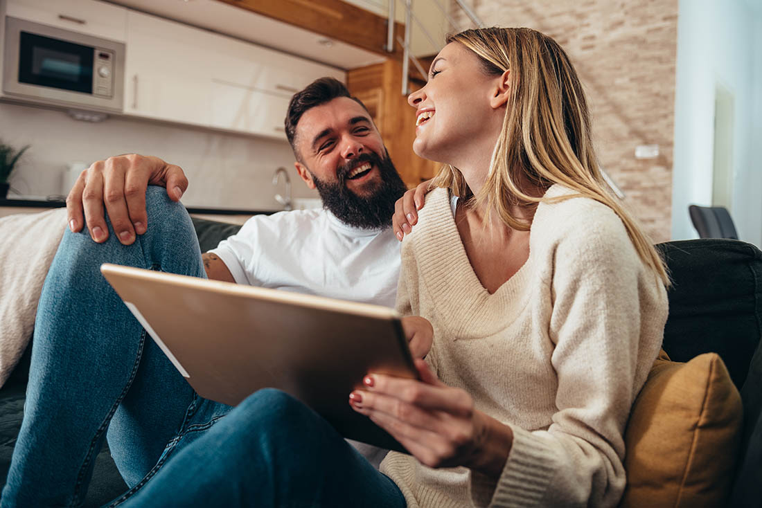 Couple sitting with their tablet laughing