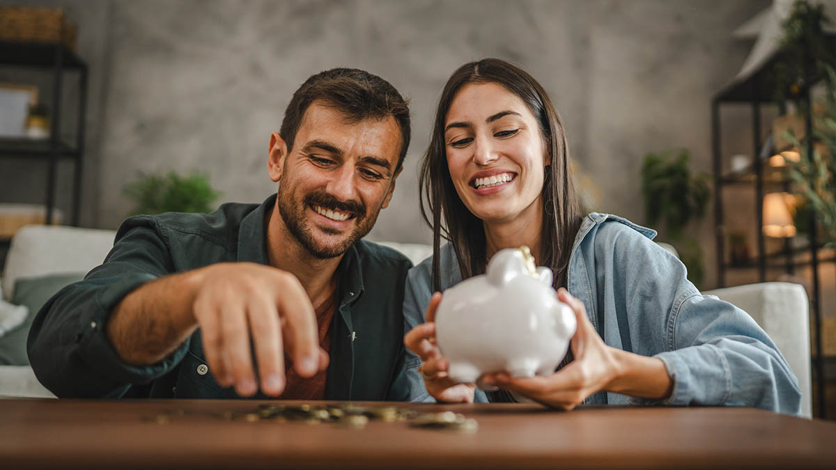 Adult couple counting coins out of a piggy bank